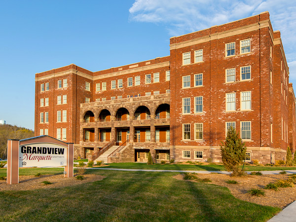 Photograph of the front facade of a large five-story brick building with sandstone accents.