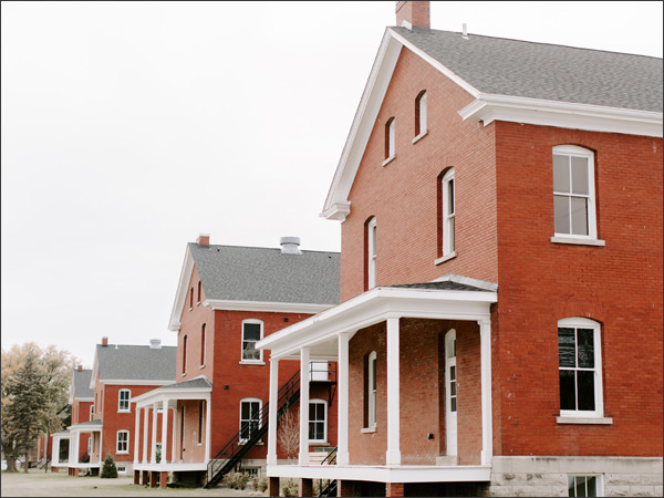 Photograph of four two-story red brick buildings with white-painted front porches.