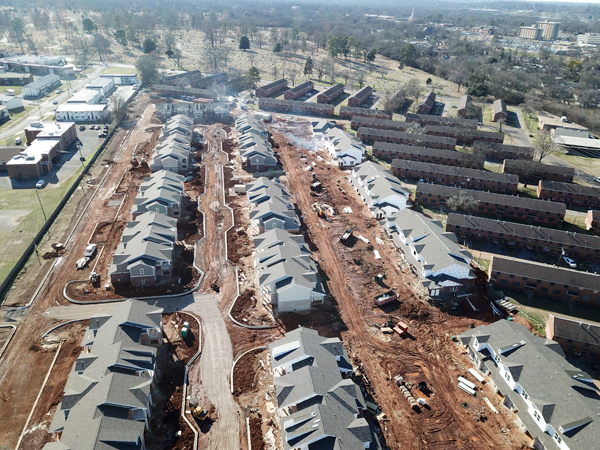 Aerial photograph of housing development showing newly built multifamily buildings surrounded by old, barracks-style multifamily buildings.