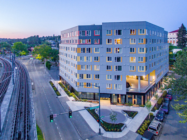 Image of an eight-story apartment building next to rail lines