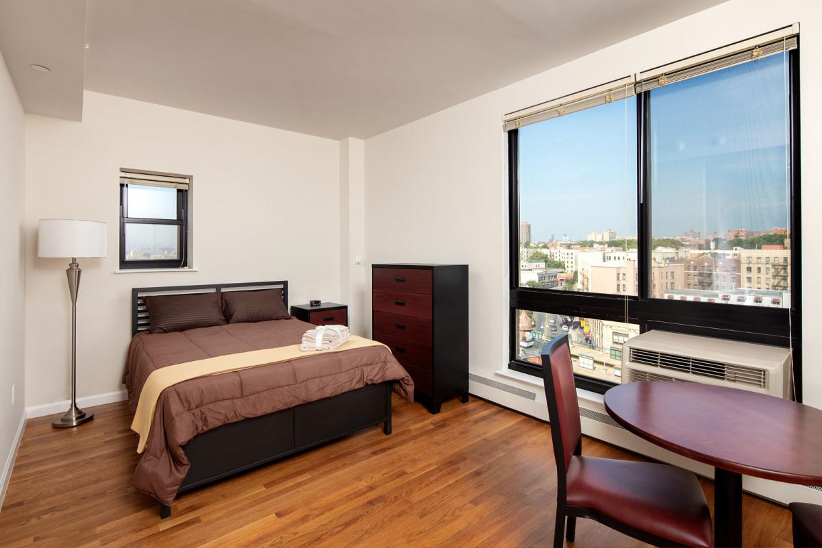 Image of a studio apartment with bed and small dining table.