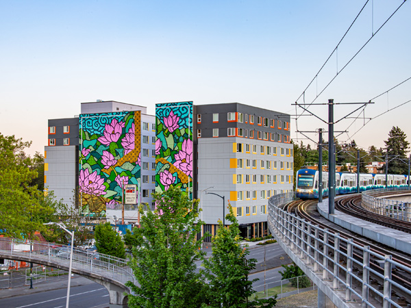 Image of a new apartment building with a multi-story mural painted on one side.