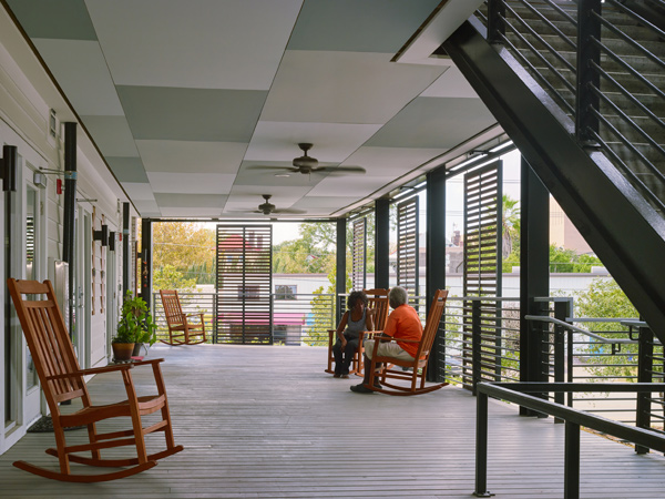 Image of two people sitting in rocking chairs conversing on a covered porch.