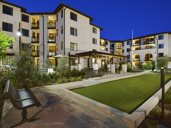 Image of an outdoor bocce court next to a multifamily apartment building.