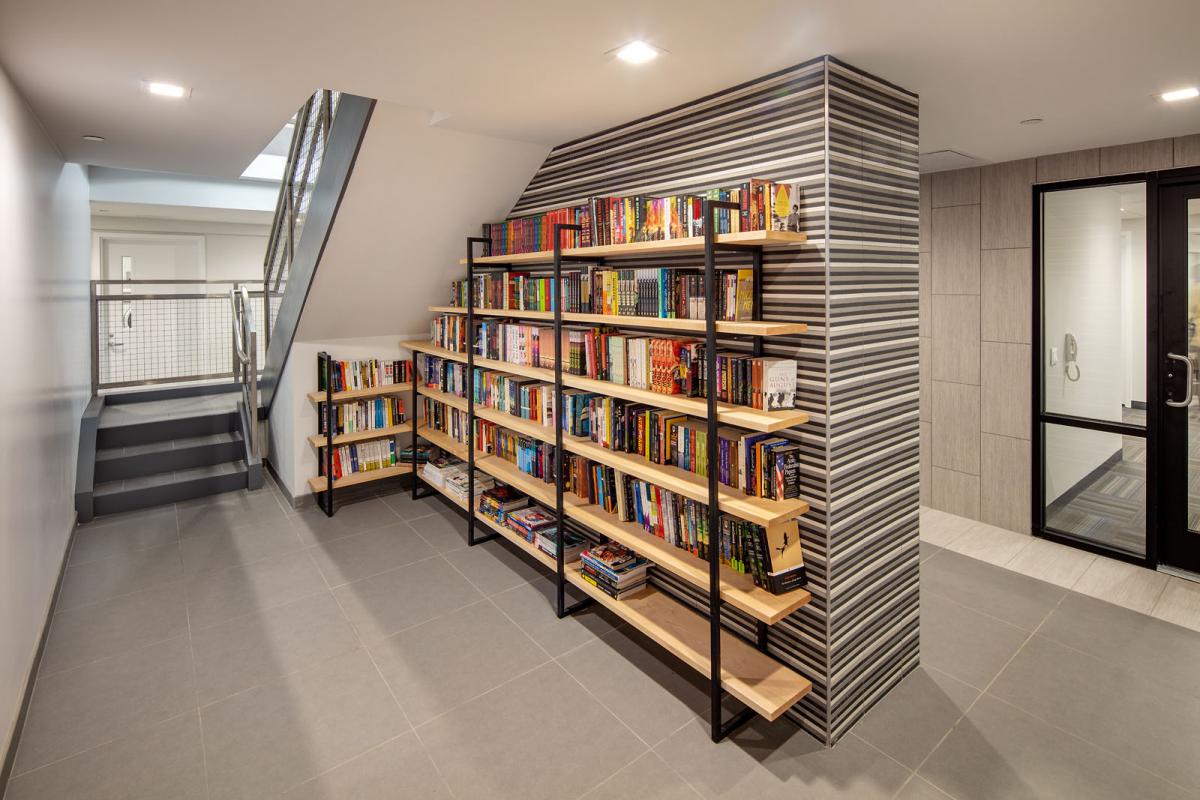 Image of books on shelves tucked under an apartment building staircase.