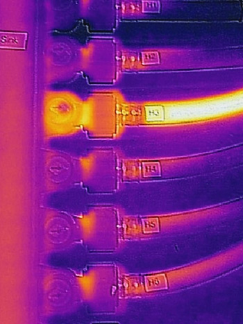 Thermal image of a plumbing manifold and tubing, where the tube through which hot water is flowing is visible.