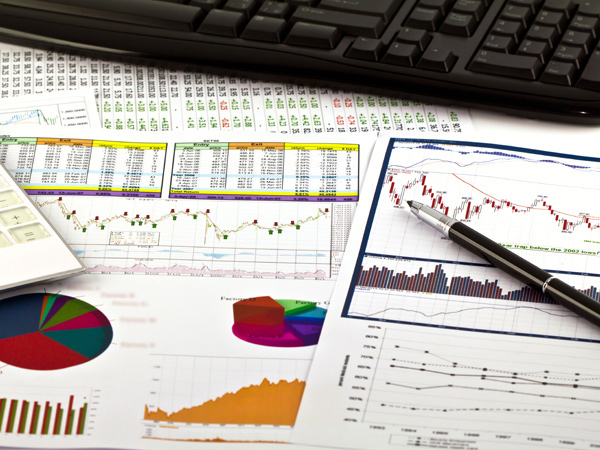 Papers with charts and spreadsheets. A computer keyboard is visible in the background.