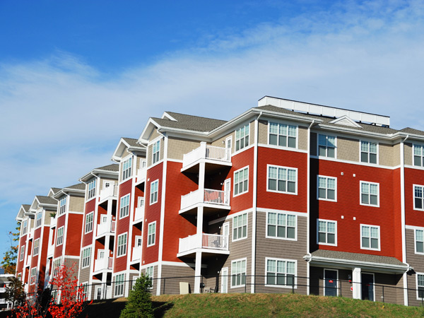 Photograph showing two sides of a multi-story, multifamily residential building. 