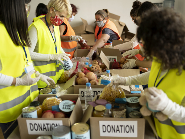 Photo of a group of volunteers putting canned and bagged food in donation boxes.