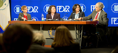 Image showing four individuals, Assistant Secretary for Policy Development and Research Katherine O'Regan, HUD senior leadership, including Harriet Tregoning, Lourdes M. Castro Ramirez, and Edward L. Golding seated at a table bearing the HUD logo. An image with the HUD and PD&R logos is visible on a screen behind the table.