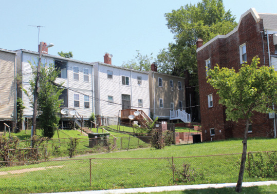 A photo of rear view of row houses with  grassy area in the foreground.