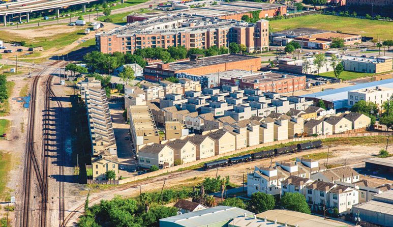 An aerial view of a Houston neighborhood showing different multifamily developments and railway tracks on the left.