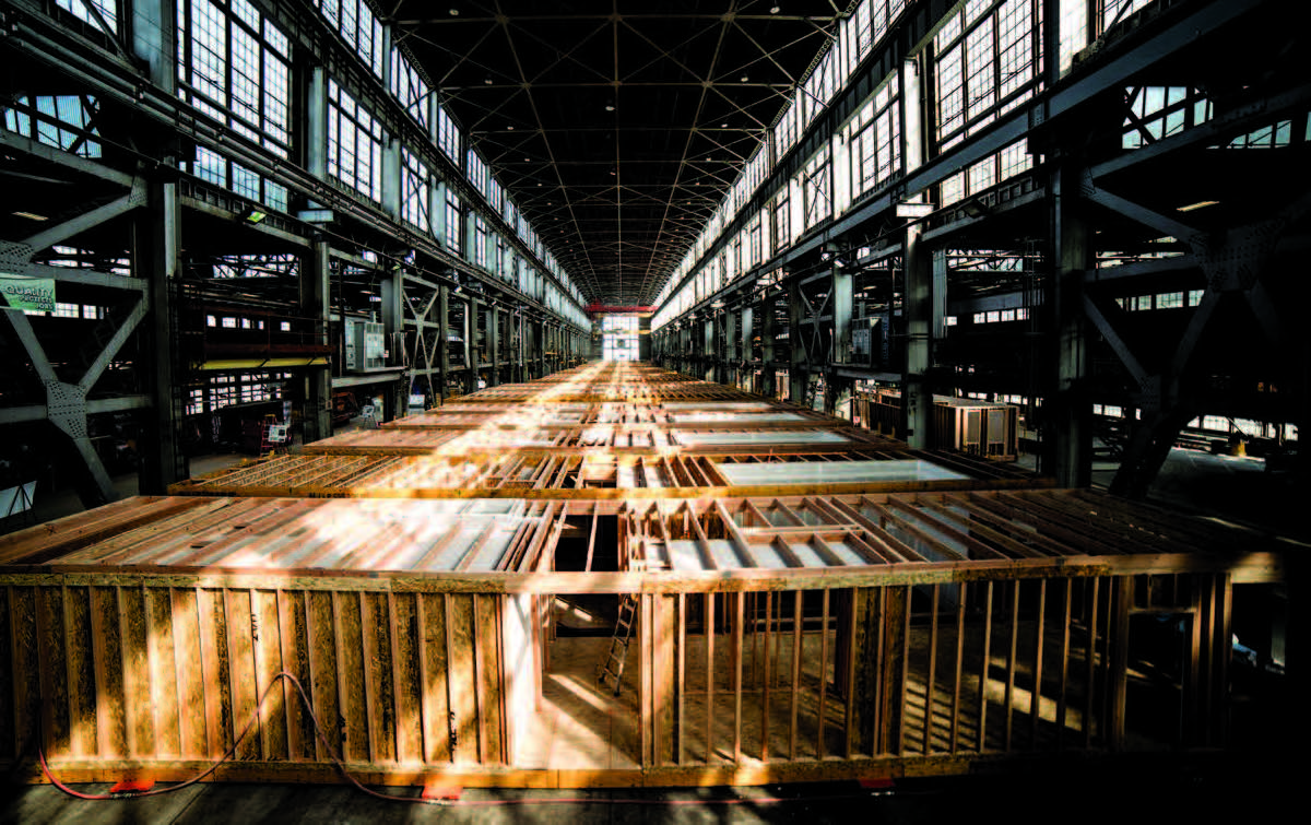 Interior of a factory with wood framed housing components on the factory floor.