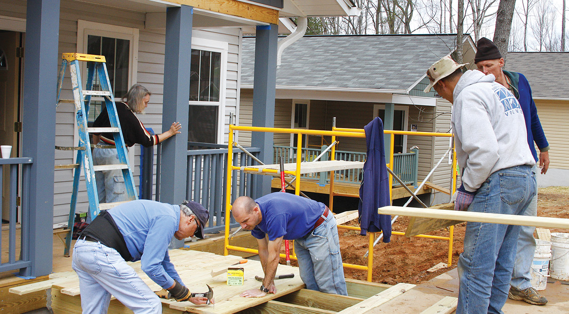 Photo shows five volunteers working on a home under construction.