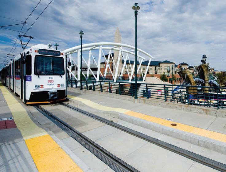 Photo shows light rail train stopped at a station in Denver.