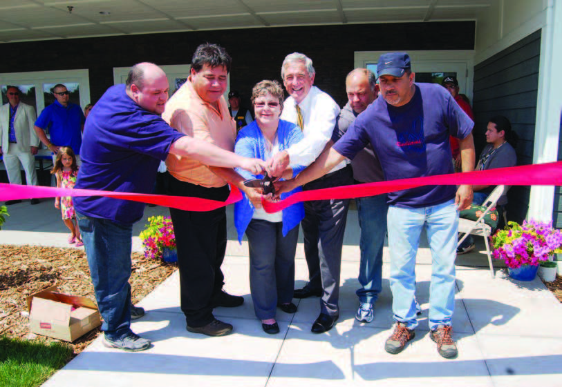 Five members of the Fond du Lac Band of Lake Superior Chippewa Indians and Rep. Rick Nolan cutting a ribbon in front of a housing development.