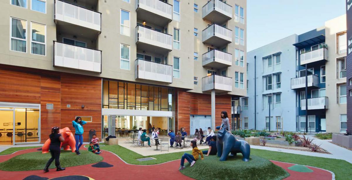 Kids in a play area situated within a courtyard surrounded by apartment buildings