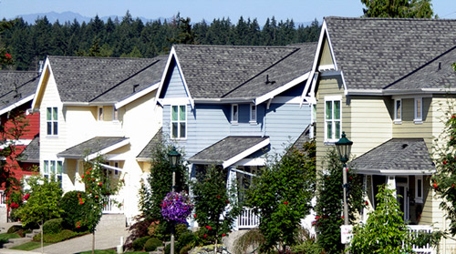 Photograph of five multi-story, single-family detached homes in a row along a street.