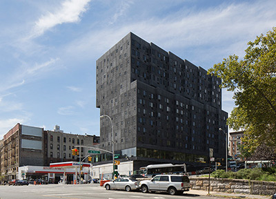 Photograph of the northern and eastern façades of a thirteen-story multifamily building.