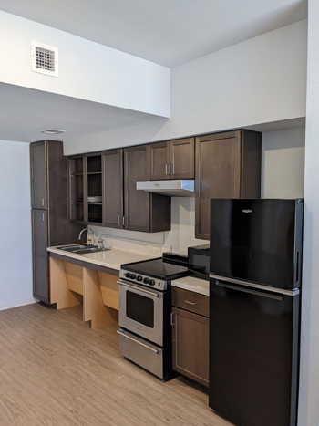 An interior unit with a full kitchen that includes a refrigerator, microwave, oven, sink, and cabinetry above and below. 