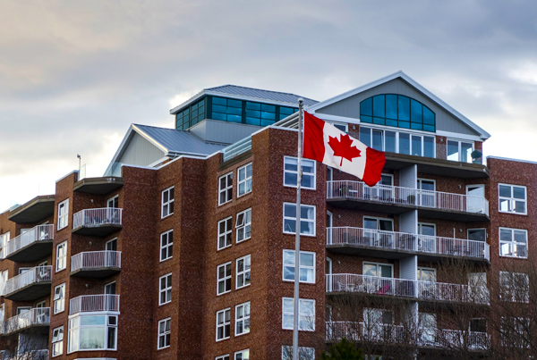 A multistory residential building with a Canadian flag in front.