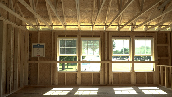 Photo of the interior of SBCA's two-story housing demonstration, showing construction built with panelized walls, roof truss, and floor assembly systems.