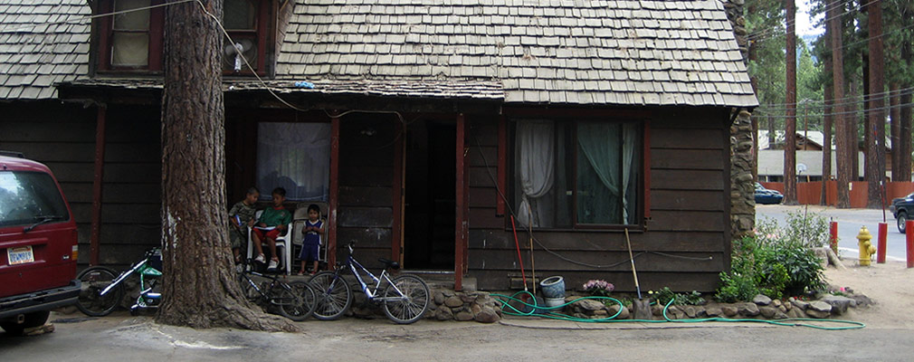 Photograph of a one-and-one-half-story house with wood siding and a pitched roof covered in wooden shingles.