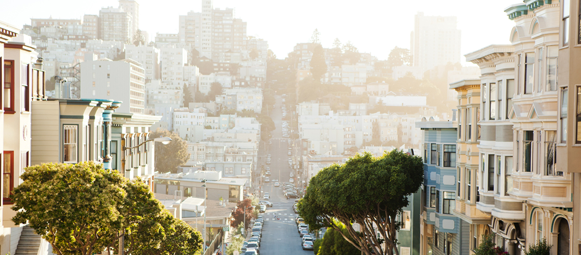 Photograph of a steep San Francisco street lined with buildings and trees. Photograph of a steep San Francisco street lined with buildings and trees.