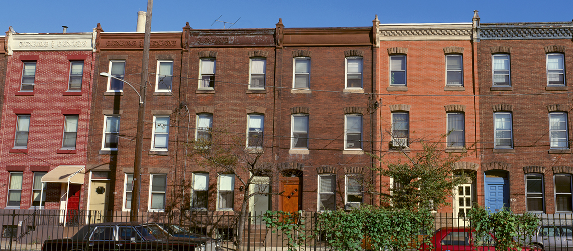 Image of three-story brick rowhouses on a city block. Image of three-story brick rowhouses on a city block.