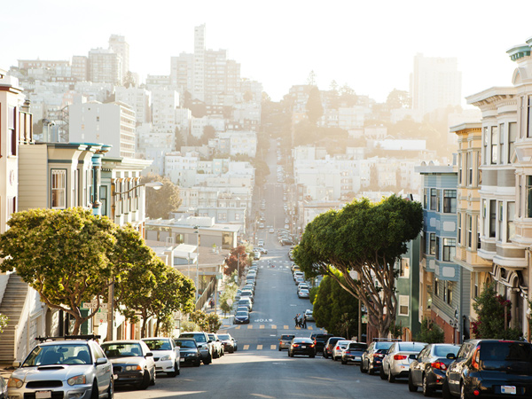 Photograph of a steep San Francisco street lined with buildings and trees. Photograph of a steep San Francisco street lined with buildings and trees.