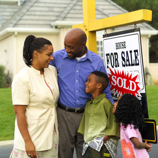 A picture of a minority family next to a home they have just purchased.