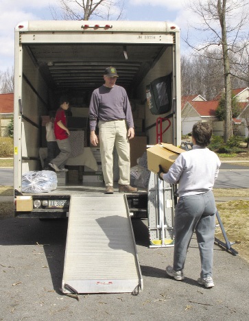 A family loading boxes onto a moving truck.