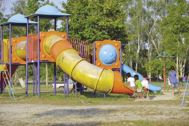 Children using playground equipment in a neighborhood park.