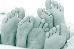 A picture of three pairs of feet huddled together.