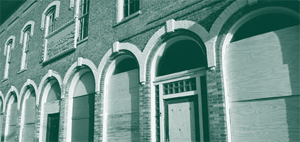 A picture of a large brick building with boarded-up windows.