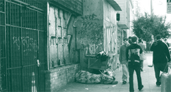 A picture of a homeless person sleeping on the pavement.