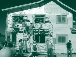 A picture of Bike and Build participants helping to install siding and insulation on a building.