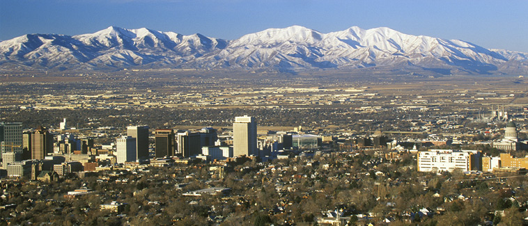 Skyline view of Salt Lake City, Utah with snow-covered Wasatch Mountains in the background.