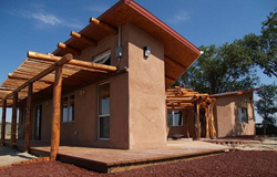 Exterior image of the Nageezi House, a single family detached home built using aerated flyash concrete block, and its attached shade structure.