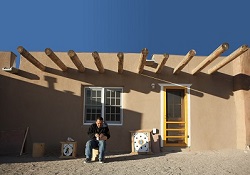 Image of a man sitting in front of a home in Owe’neh Bupingeh, the site of a multiphased project that emphasizes the importance of contemporary life and cultural traditions that comfortably coexist.