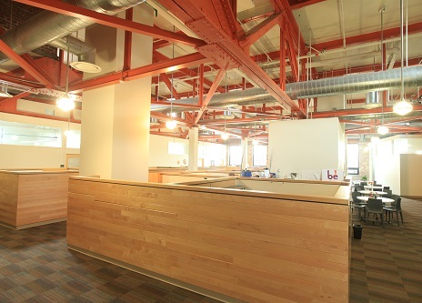 Photograph of the inside of the Business Development Incubator at New Jersey City University showing an open floor plan with cubicle partitions. Exposed rafters and mechanical systems create an open and airy space.
