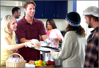 A picture of volunteers serving a meal to homeless people