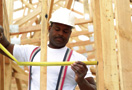 Construction worker in hard hat measuring between studs.