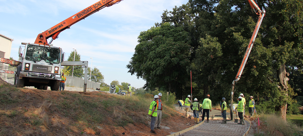 A photograph shows a truck pouring concrete to form the path along a portion of the Westside Trail.