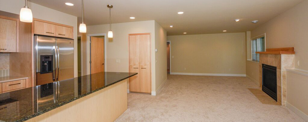 An interior view of a dwelling unit showing part of the kitchen and the unfurnished living area.