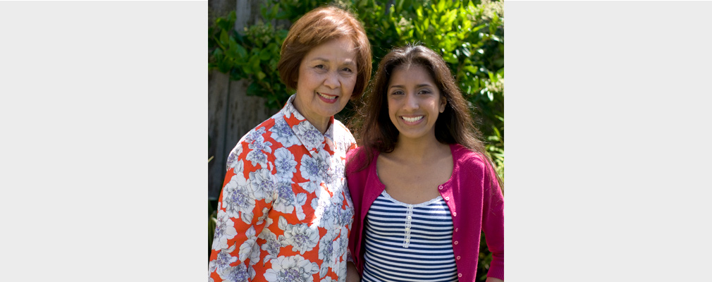 An older woman and a younger woman pose for a photo standing next to each other.