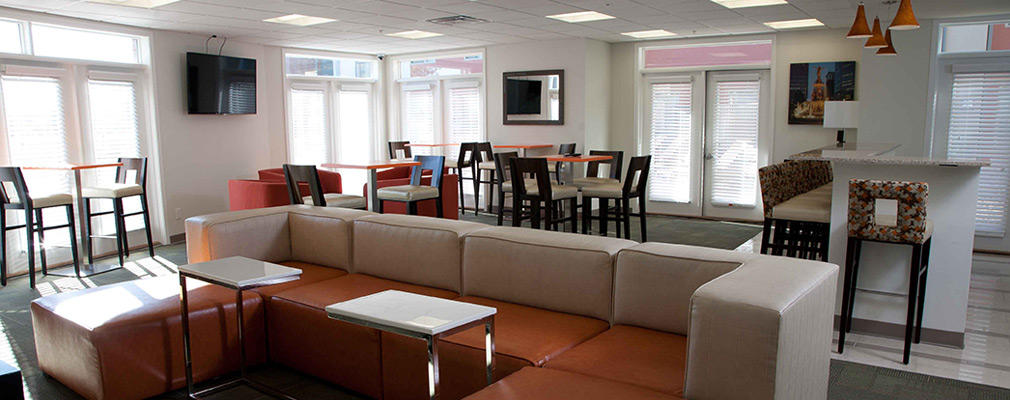 Photograph of a club room with couch, several tables, and a bar.