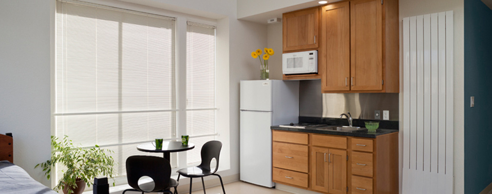 Photograph of the interior of a studio showing the dining area and kitchenette.