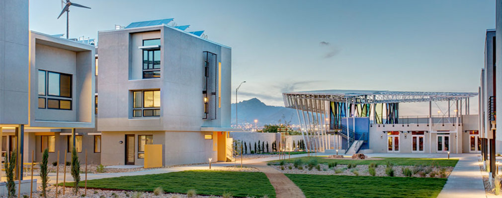 Photograph of the northern portion of the development, with solar panels on the roof of the multifamily building and a wind turbine in the background.