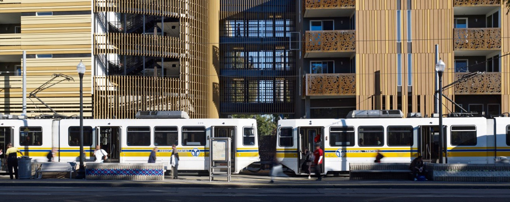 Photograph showing portions of two four-story apartment buildings joined by walkways on the upper three stories.